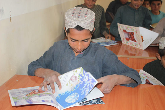 Happy student in Zarghoon Kalai school reading Hoopoe books