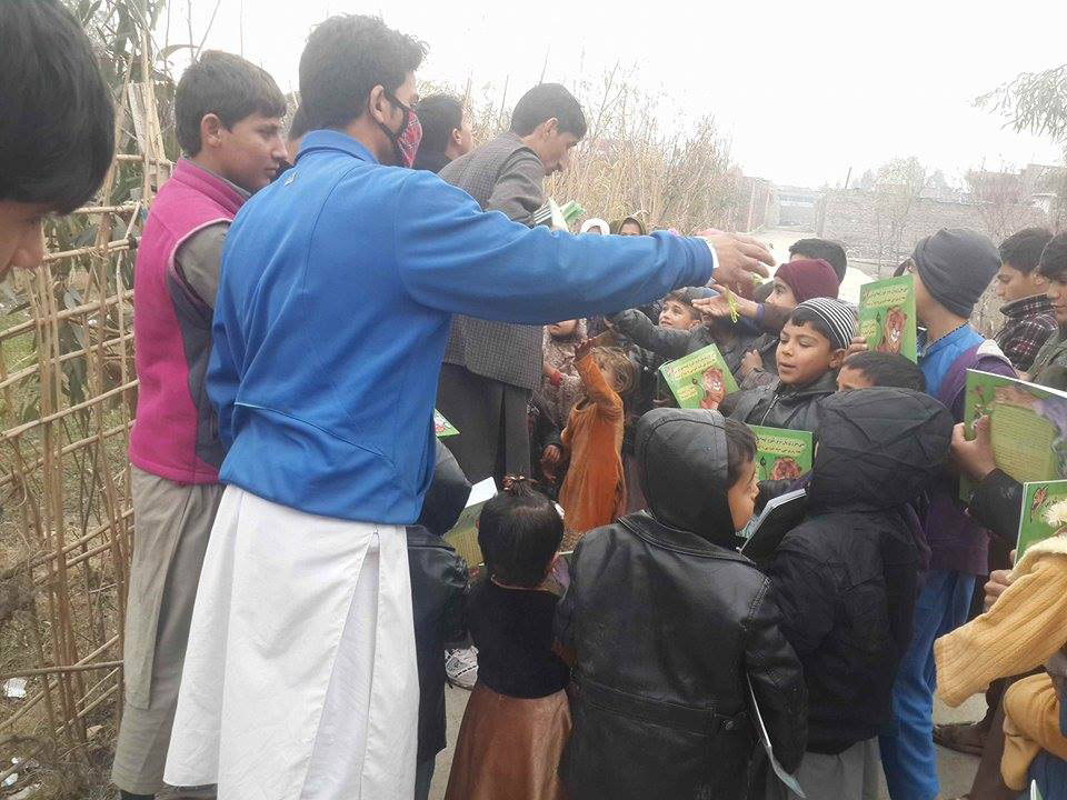 Afghan kids crowd around waiting to receive a copy of the Sawji-Pashto edition of The Lion Who Saw Himself in the Water